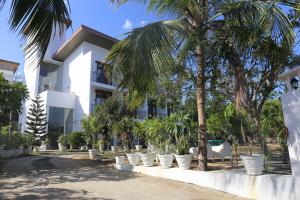 a white building with palm trees in front of it at Amanda Beach Resort in Pasikuda