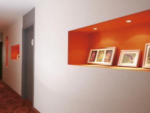 a hallway with orange walls and framed pictures on a shelf at Kurhaus Pivittskrug in Hille
