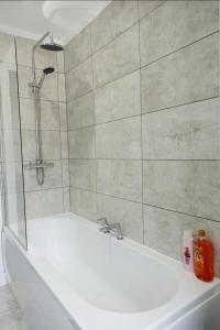 玛丽波特West Lake District Comfort Stays in Maryport town centre的带淋浴和白色浴缸的浴室