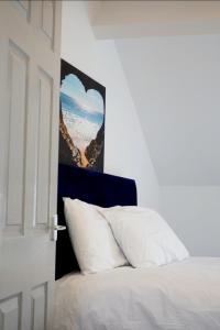a bedroom with a white bed with a heart picture on the wall at West Lake District Comfort Stays in Maryport town centre in Maryport