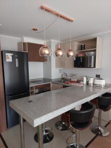 a kitchen with a large counter with stools in it at Bienvenido a Valdivia II in Valdivia