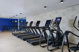 - une salle de sport avec une rangée de tapis de course et de vélos elliptiques dans l'établissement Delta Hotels by Marriott New York Times Square, à New York