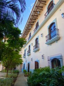 a large white building with balconies and trees at Hotel La Recolección in León