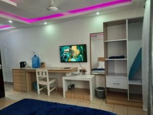 Cette chambre dispose d'un bureau et d'un lit avec des lumières violettes. dans l'établissement Seaesta Studio Diani Beach, à Diani Beach