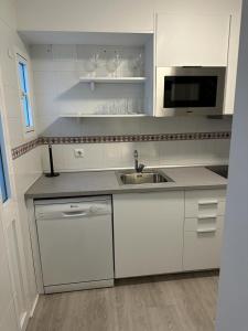 a white kitchen with a sink and a microwave at Ameyal Madre Rafols in Seville