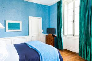 een slaapkamer met blauwe muren en een bed en een televisie bij Chambres d'Hôtes Eden Ouest in La Rochelle