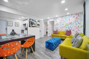 a living room with a yellow couch and orange chairs at Vacay Spot Wynwood Retreat 6 to 42 Guests 6 Kitchens Shower Massage jets, BBQ, Patio LED vibes, Prime LOC! 6 blocks away 4rm Bars, Nite Clubs, Res, Shops in Miami