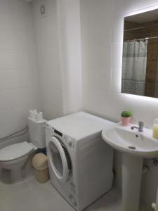 a white bathroom with a washing machine and a sink at Kosara in Skopje