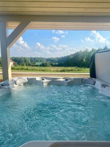 a jacuzzi tub in a backyard with a view at Osada Skoczkowo domki z kominkami, jacuzzi, balią i sauną nad jeziorem in Podiazy