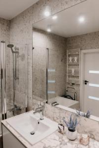 łazienka z umywalką i dużym lustrem w obiekcie Jak u siebie w domu. Apartament w nowej dzielnicy. w Tczewie