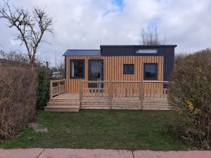 une petite maison avec une grande terrasse en bois dans l'établissement Camping De Grienduil, à Nieuwland