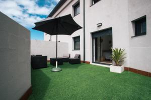 un patio con sombrilla y césped verde en Laxiela Apartment en O Grove