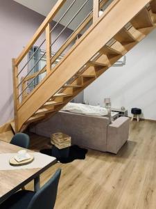 a living room with a bed under a staircase at Gîte Cosy au cœur de l'Alsace in Roggenhouse