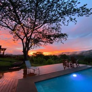 a swimming pool with a tree and a sunset at Luxury Villa Caoba- Private, Serene, Amazing Views in San Mateo