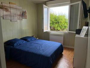 a bedroom with a blue bed and a window at Maison les pieds dans l'eau in Quinéville