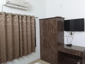 a room with a television and a wooden curtain at GRG Kanha Inn Lucknow in Lucknow