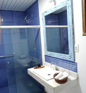 Baño de azulejos azules con lavabo y espejo en Machê Pousada & Boutique - A mais charmosa de Arraial D ajuda, en Arraial d'Ajuda