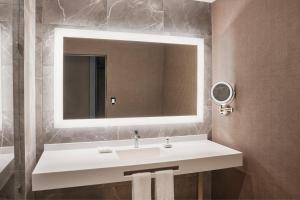 een badkamer met een witte wastafel en een spiegel bij AC Hotel by Marriott Saltillo in Saltillo