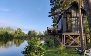 a cabin next to a lake with a balcony at Dragon house in the tree! Jacuzzi, Sauna ,apkure! in Līči