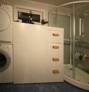 y baño blanco con ducha y lavadora. en Privat hjem i Grimstad - Nær Arendal og Dyreparken, en Grimstad