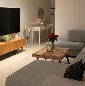 sala de estar con sofá y mesa con TV en Privat hjem i Grimstad - Nær Arendal og Dyreparken en Grimstad