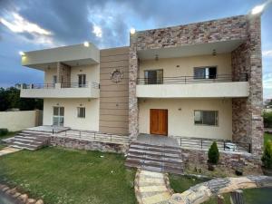a large house with a lawn in front of it at فيلا للايجار اليومى اوالشهرى فى الريف الاوربي- طريق مصر اسكندرية الصحراوى- قريبة من مطار سفنكس -بجوار هايبر وان الصحراوى in Qaryat ash Shamālī