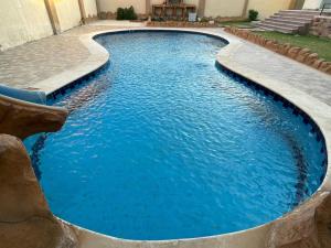 a swimming pool with blue water in a yard at فيلا للايجار اليومى اوالشهرى فى الريف الاوربي- طريق مصر اسكندرية الصحراوى- قريبة من مطار سفنكس -بجوار هايبر وان الصحراوى in Qaryat ash Shamālī +7 photos