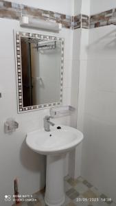 La salle de bains est pourvue d'un lavabo blanc et d'un miroir. dans l'établissement Chez Mamanta Studio meublé à St louis, à Saint-Louis