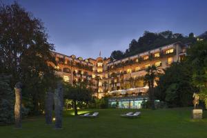- un grand bâtiment avec des chaises longues devant dans l'établissement Grand Hotel Villa Castagnola, à Lugano