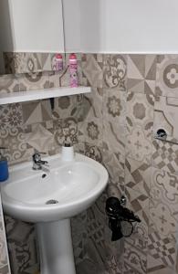 um lavatório branco numa casa de banho com azulejos em Sabbia del Sud Affittacamere em Rosolini