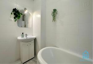 a white bathroom with a sink and a bath tub at Ocular Room in Gdańsk