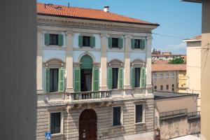 um edifício antigo com persianas verdes e uma varanda em Maison Calcirelli rooms em Verona