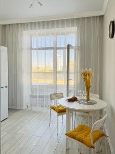 a white dining room with a table and chairs at Alma Park in Taldykolʼ +85 photos