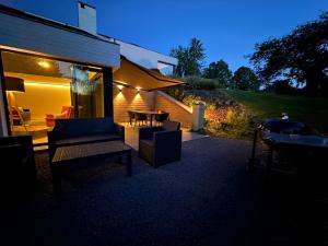 eine Terrasse mit Sofas und einem Tisch vor einem Gebäude in der Unterkunft Sakura Lodging in Bossut-Gottechain