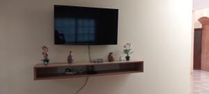 TV de pantalla plana en una pared con estantería en Las buganvilias en Pachacamac