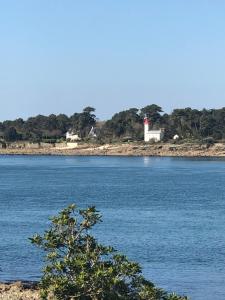 a large body of water with a lighthouse in the distance at Le Studio in Bénodet