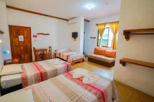 une chambre d'hôtel avec deux lits et un canapé dans l'établissement Galapagos Verde Azul, à Puerto Ayora