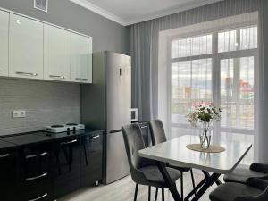 a kitchen with a table with chairs and a refrigerator at Alma Park in Taldykolʼ