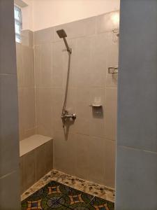 a shower stall in a bathroom with a tile floor at Maison d'hôtes Akany Fifaliana in Antananarivo