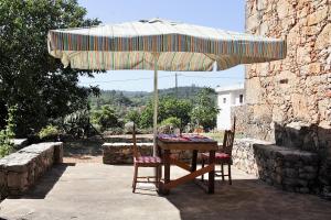 a table and two chairs under an umbrella at Casa do Loureiro in Ferrarias