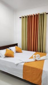 sypialnia z łóżkiem z pomarańczową i białą pościelą w obiekcie Calm Guest w mieście Trikunamalaja
