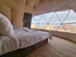 ein Schlafzimmer mit einem Bett und einem großen Fenster in der Unterkunft Travel Wadi Rum in Wadi Rum