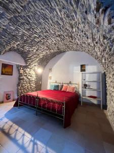 a bedroom with a red bed in a stone wall at Casa Victoria - Full equipped stone house in Rocchetta Nervina