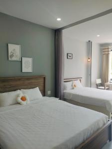 una camera con due letti con lenzuola bianche di I Play Inn NT a Nha Trang