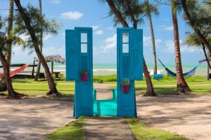 a blue door in a park with palm trees at Pousada Xalés de Maracaípe in Porto De Galinhas