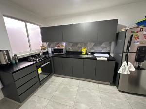 a kitchen with black cabinets and a stainless steel refrigerator at Gaston2 in Medellín
