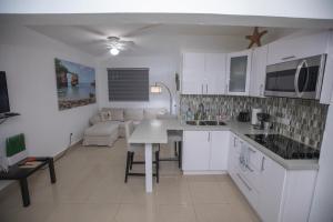 uma cozinha com armários brancos e uma sala de estar em El Velero 203 en Boquerón em Boqueron