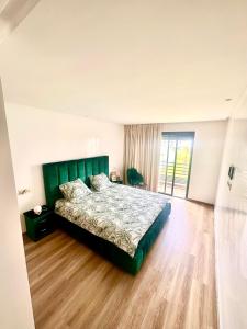 a bedroom with a green bed and a wooden floor at Appartement Cozy avec piscine in Sidi Rahal