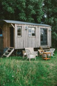 een kleine houten hut met stoelen en een tafel bij Infinite Skies Tipi's in Heydon