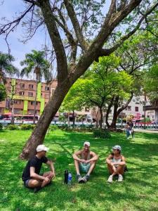 três homens sentados na relva debaixo de uma árvore em Gaston2 em Medellín